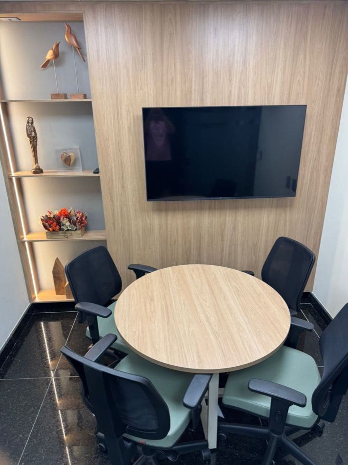 Sala de reunião pequena com mesa redonda e estante decorada